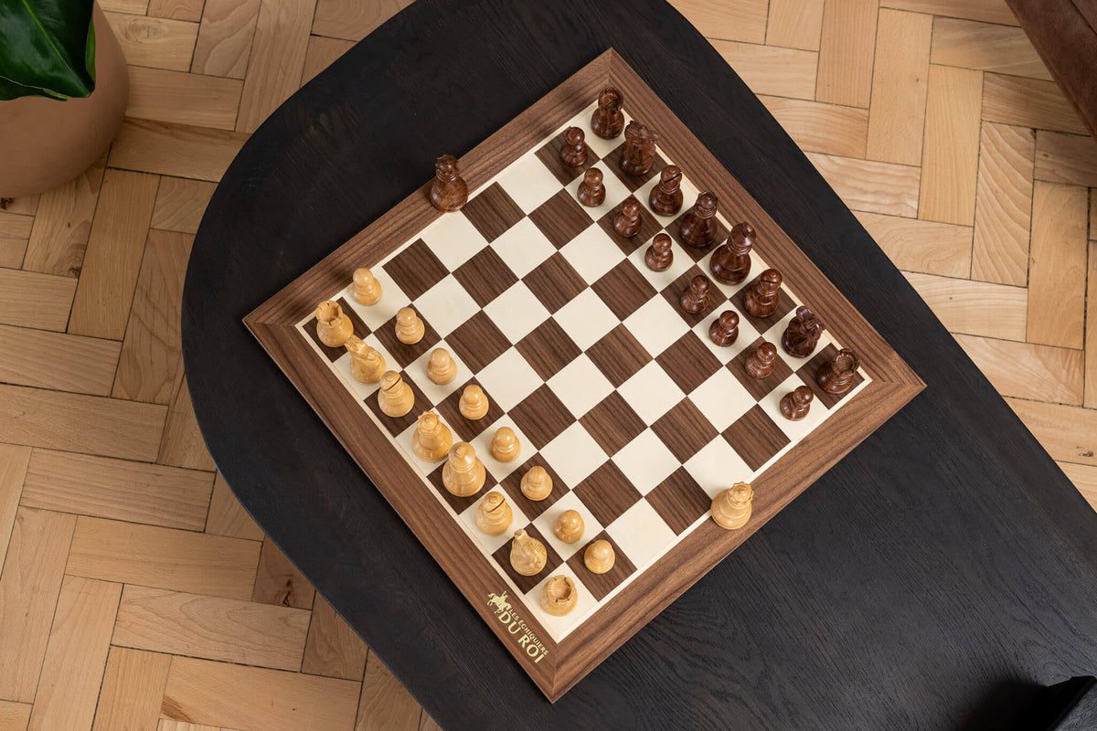 Vue de dessus d’un échiquier en bois sur une table noire dans un intérieur